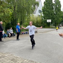 Ein Läufer wird von Mitschülerinnen und Mitschülern angefeuert