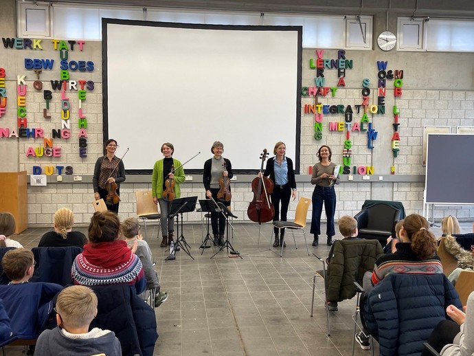 Die Musikerinnen des Klenke-Quartetts und die Schauspielerin Astrid Rashed stehen in der Aula.
