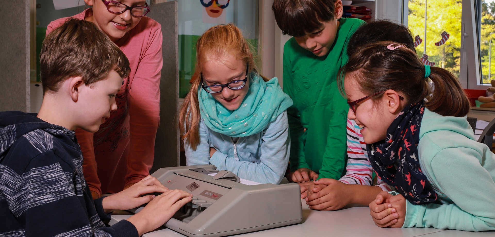 Kinder üben den Umgang mit einer Punktschriftmaschine