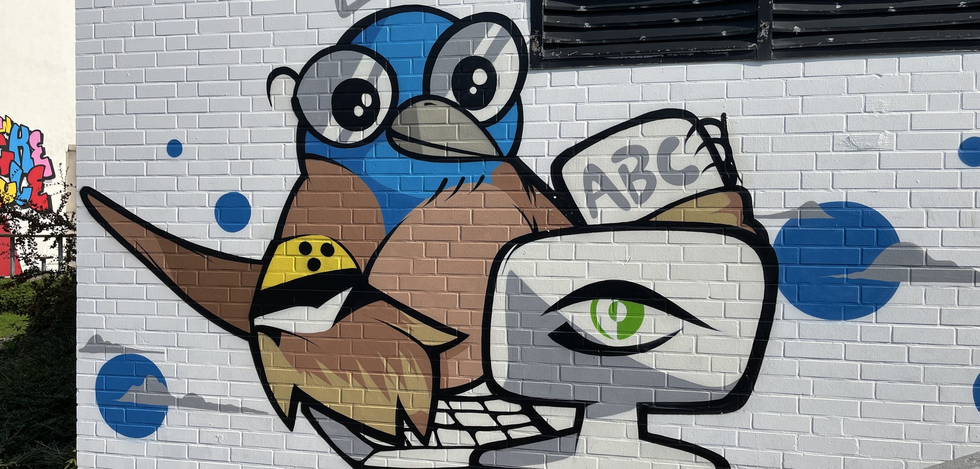 Graffiti: Ein Vogel (ein "Vinck") sitzt vor einem Computermonitor. In einem Flügel hält er ein Buch, am anderen Flügel trägt er eine Blindenarmbinde.