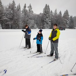 Drei Schüler stehen auf Langlauf-Ski in einer Schneelandschaft