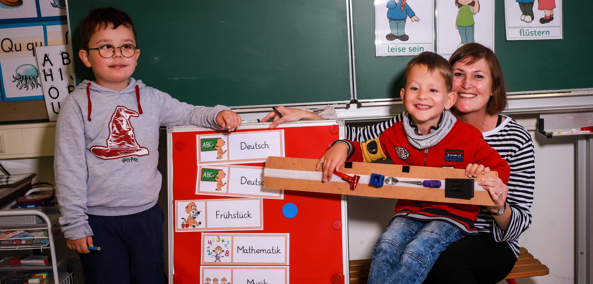 Eine Lehrerin mit zwei Grundschülern in einem Klassenzimmer