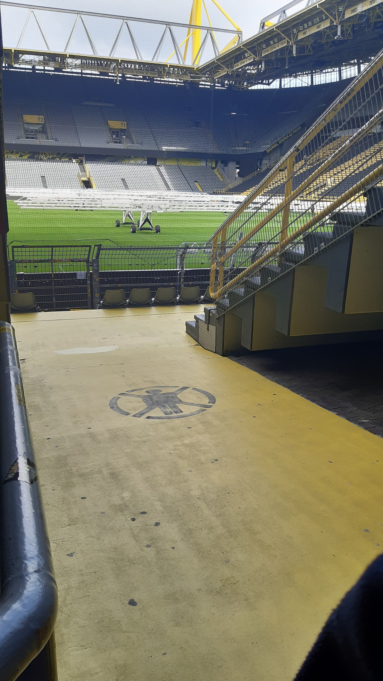 Auf dem Bild sieht man einen Durchgang zum Rasen, genauer für die Fans, die durch den Durchgang gehen, um zu den Sitzplätzen zu gelangen.